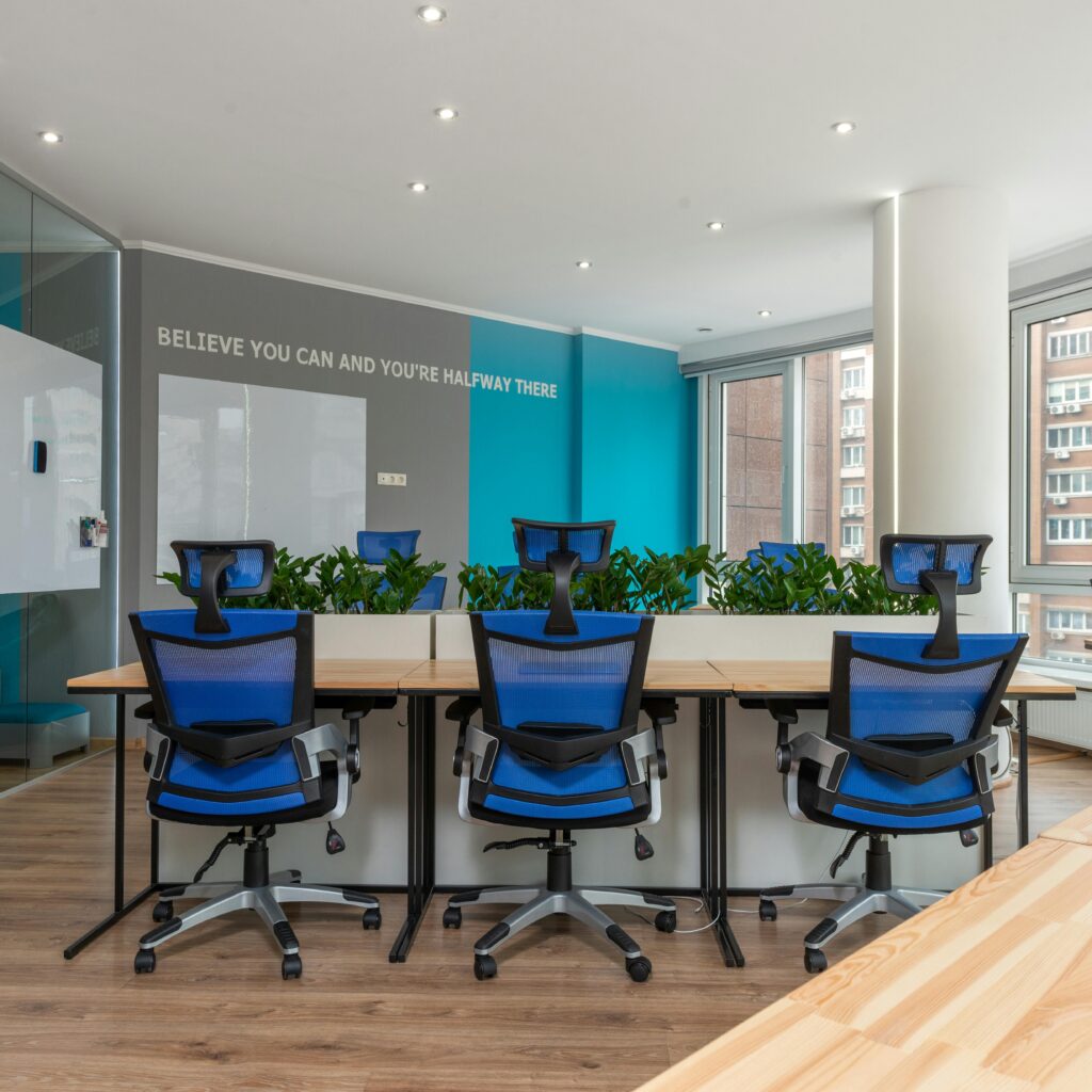 Contemporary office interior with blue chairs and greenery, promoting creativity and efficiency.