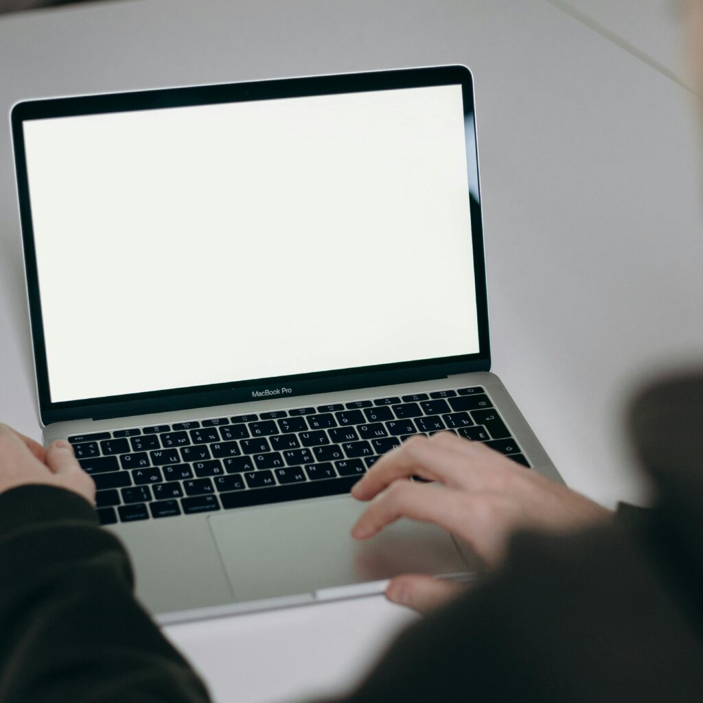 A man typing on a laptop with a blank screen at home, illustrating remote work.