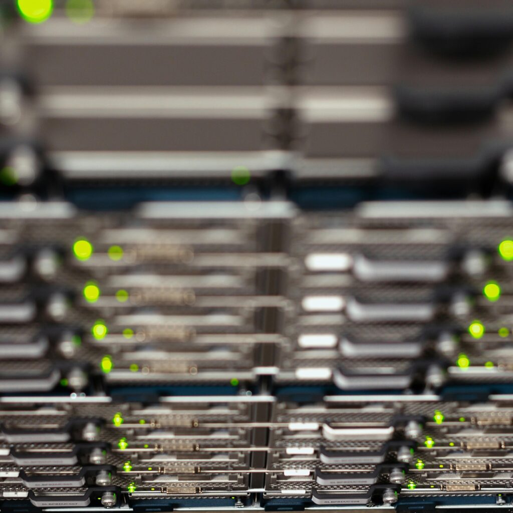 Close-up of a network server rack with blinking LEDs, showcasing Ethernet connections and patch panels.
